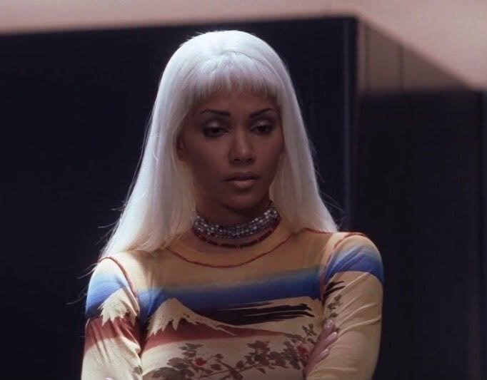 Refer to the image. In X-Men (2000), Halle Berry, playing Storm, is wearing a top from which designer?