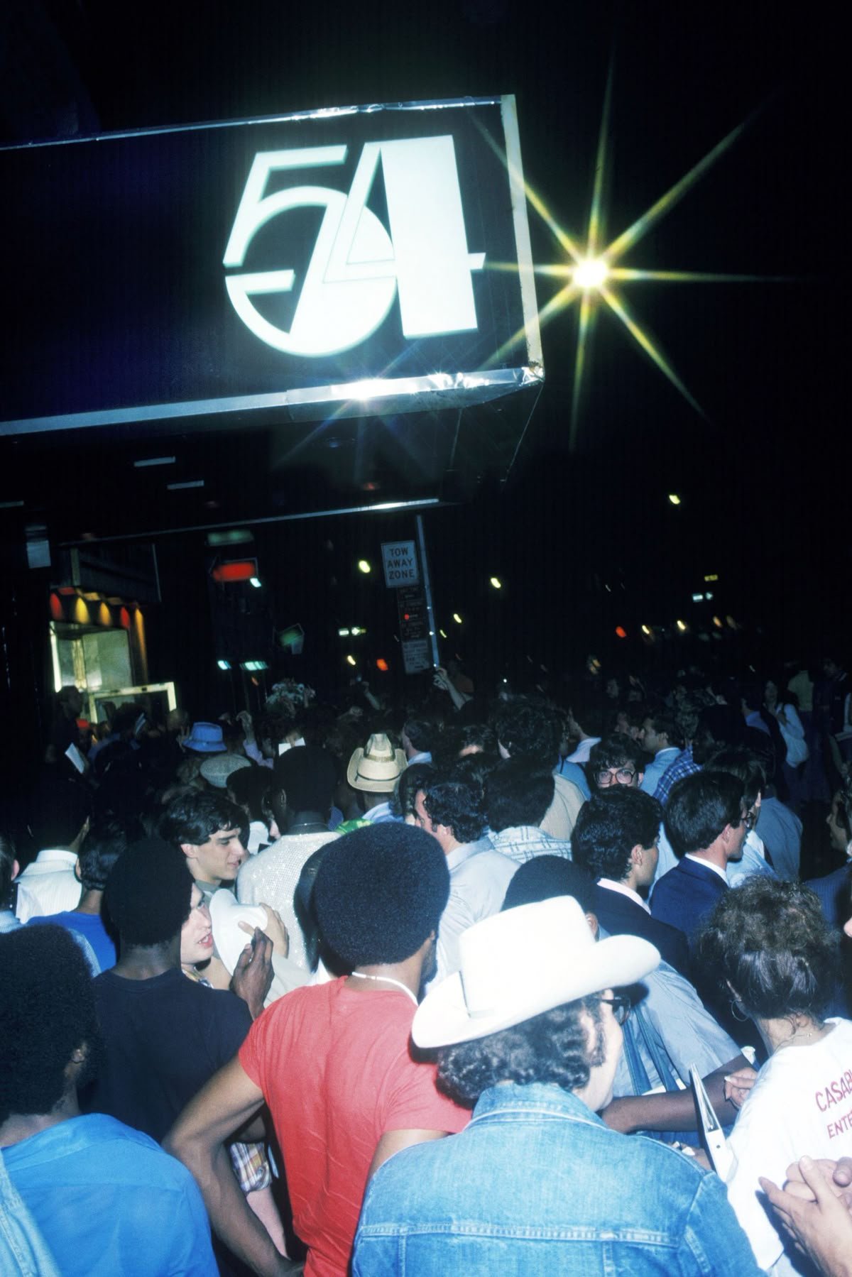 Studio 54's legendarily selective door staff reportedly banned one specific fabric outright, not because it looked wrong, but because it would physically "melt" under the club's intense stage lighting. What fabric was it?